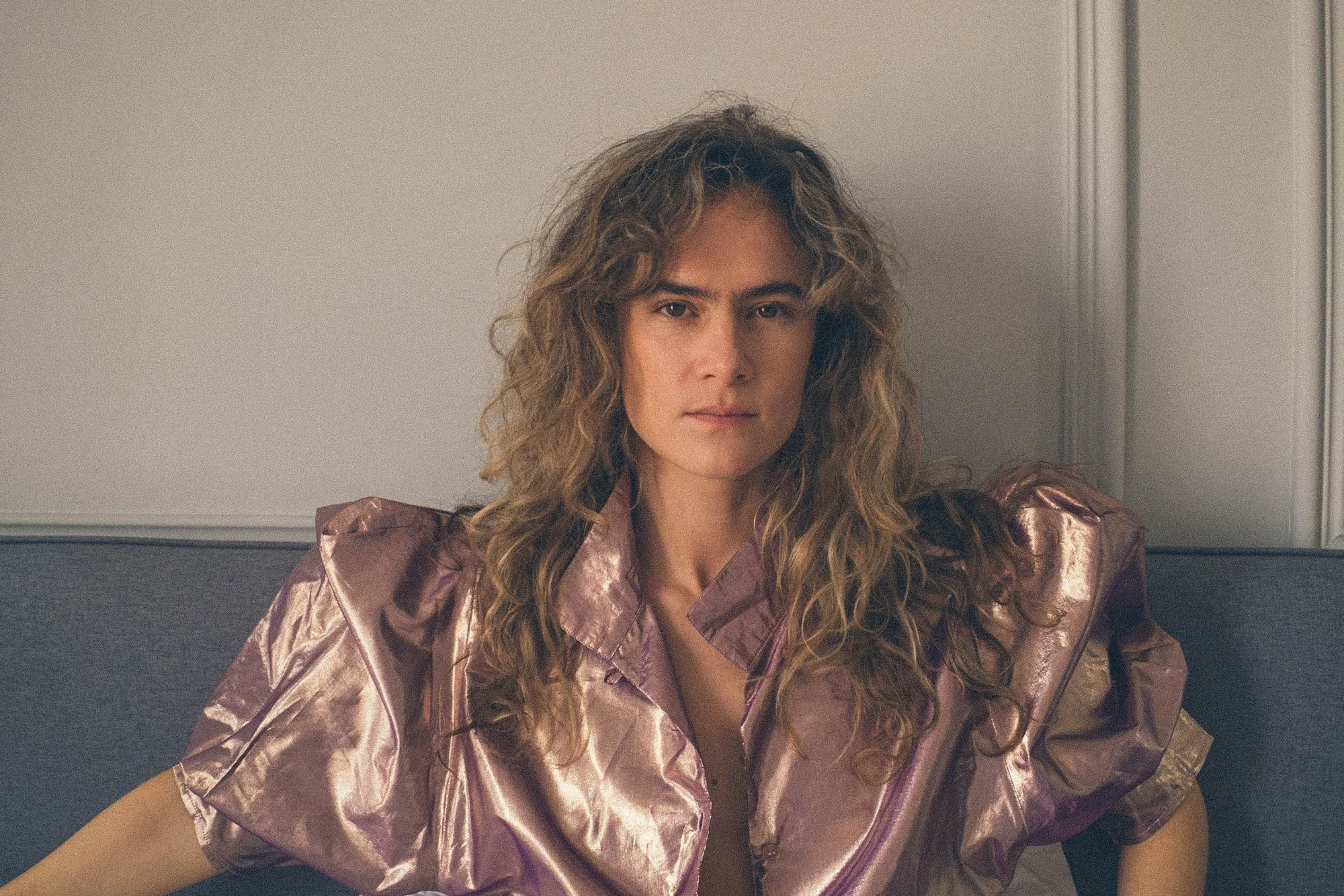 Mariola de Lope sentada en un sofá con una camisa metalizada